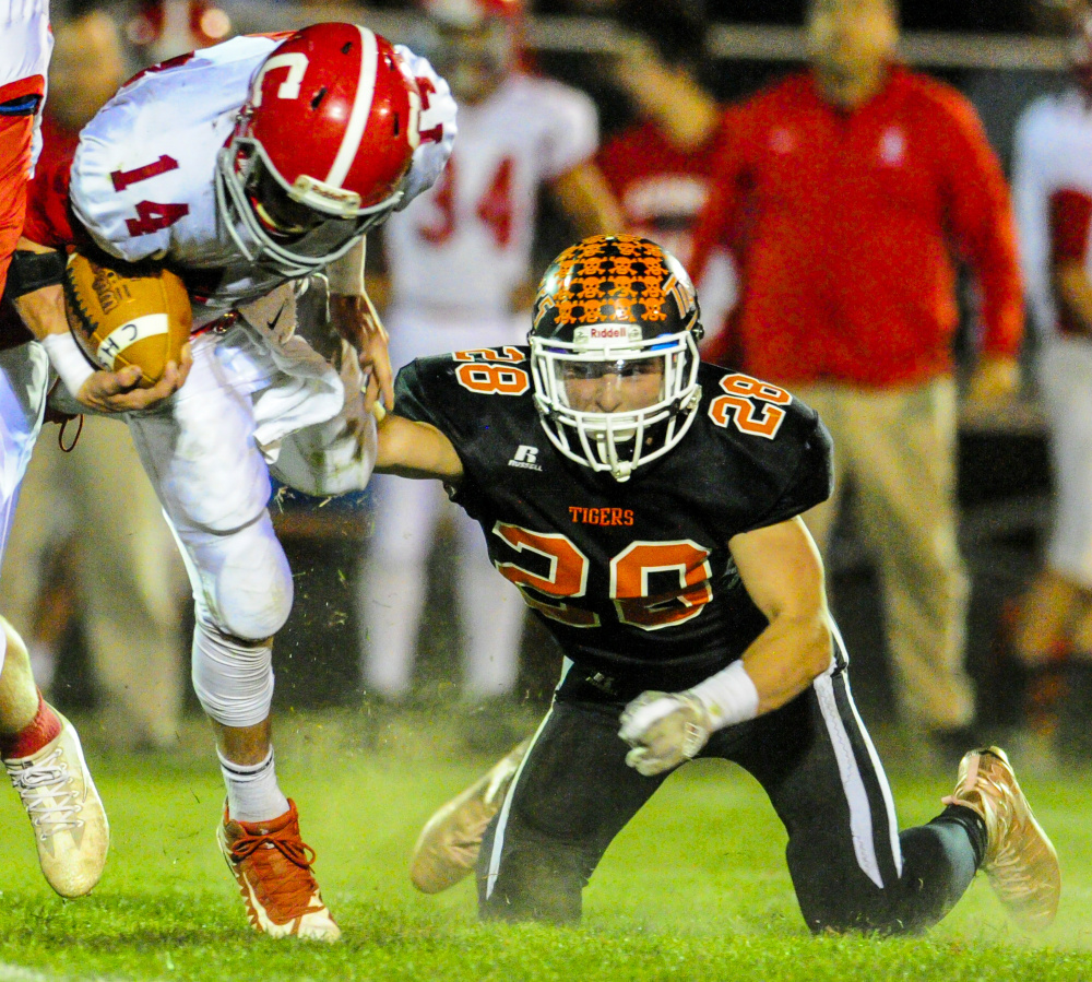 Cony quarterback Anthony Sousa gets tripped up by Gardiner's Garrett Maheux last week at Hoch Field in Gardiner.