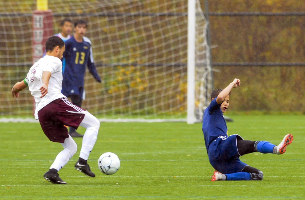 Monmouth's Nick Dovinsky moves the ball upfield as Traip's Frankie Driscoll misses a slide tackle during a rain soaked Class C South quarterfinal game Thursday at Kents Hill School.