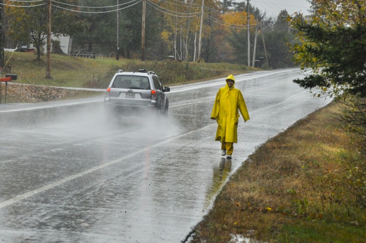 Andrew Nichols wears yellow rain gear as he walks Wednesday along Civic Center Drive in Augusta. Nichols finished his shift at Home Depot and was walking in the pouring rain to get to his home on Summerhaven Road. More rain is expected from Sunday night into Monday.