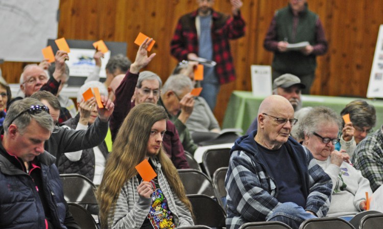 Residents hold up cards March 18 to vote during the Belgrade Town Meeting at the Center For All Seasons, where another meeting will be held Monday to discuss the town's possible withdrawal from Regional School Unit 18.