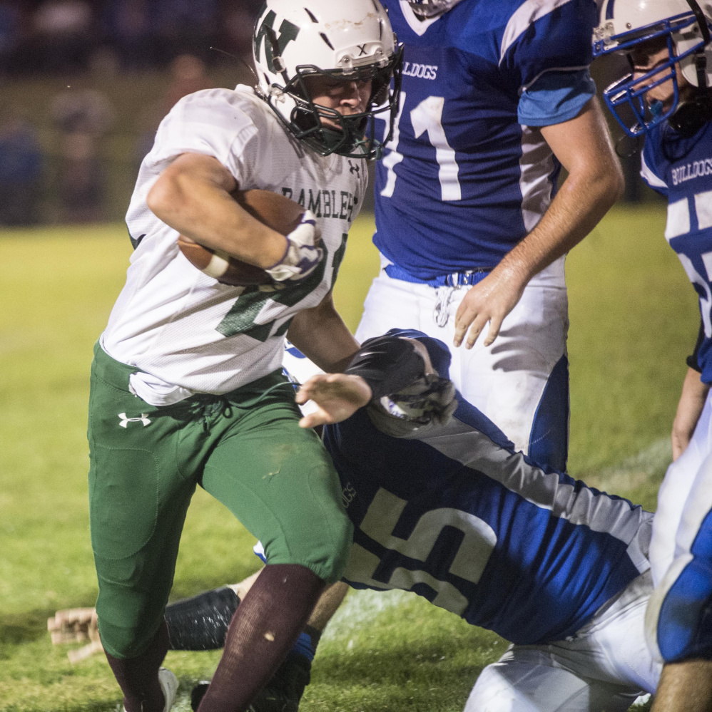 Winthrop/Monmouth running back Kane Gould runs through a tackle by Madison defender Brad Peters during a Class D South game earlier this season at Rudman Field in Madison.