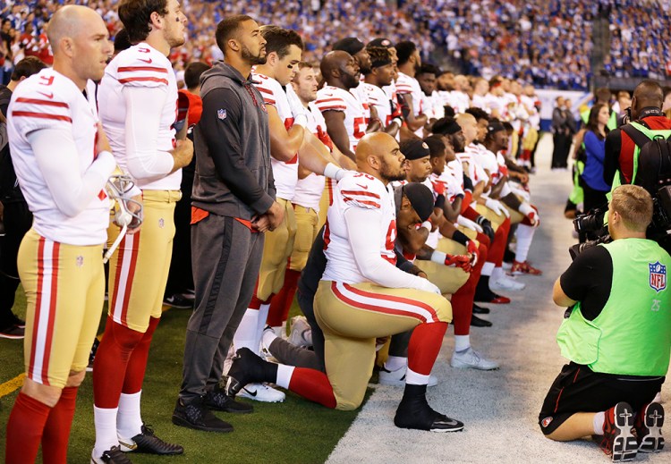About a dozen members of the San Francisco 49ers take a knee during the playing of the national anthem before an NFL football game against the Indianapolis Colts on Sunday in Indianapolis. 