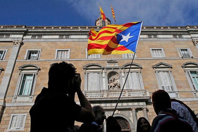 A man holds an independence flag outside the Palau Generalitat in Barcelona Monday. Catalonia's civil servants face their first full work week since Spain's central government overturned an independence declaration by firing the region's elected leaders. (AP Photo/Manu Fernandez)