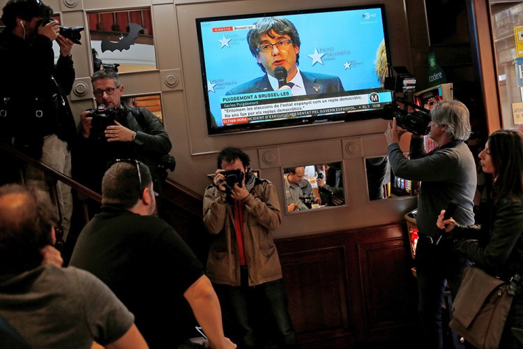 Sacked Catalan leader Carles Puigdemont is seen, during a broadcast  from Brussels, on a TV screen at a bar near  Sant Jaume square in Barcelona, Spain Tuesday. 