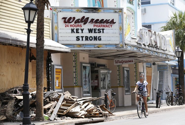 A cyclist rides past a pile of debris in Key West, Florida, recently. Irma will likely end up having caused $58 billion to $83 billion in economic losses, Moody's forecasts.