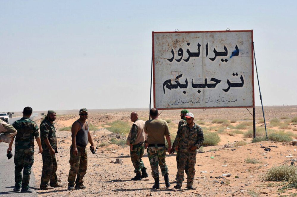 Syrian troops and pro-government gunmen gather near a sign that reads, "Deir el-Zour welcomes you," after the Syrian city was taken from Islamic State fighters earlier. The Islamic State has continued to lose ground three years after they swept through the region.