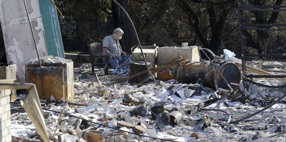 Timothy Lillyquist looks through debris at a Santa Rosa home destroyed by wildfires. Wine country got a smidgeon of rain Saturday while the mountains expected up to 2 feet of snow.