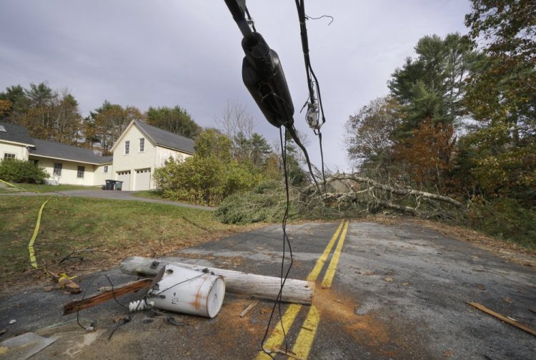 A utility pole with a transformer still attached lies in the middle of Flying Point Road in Freeport last Friday, under wires weighted down by trees that block the road.