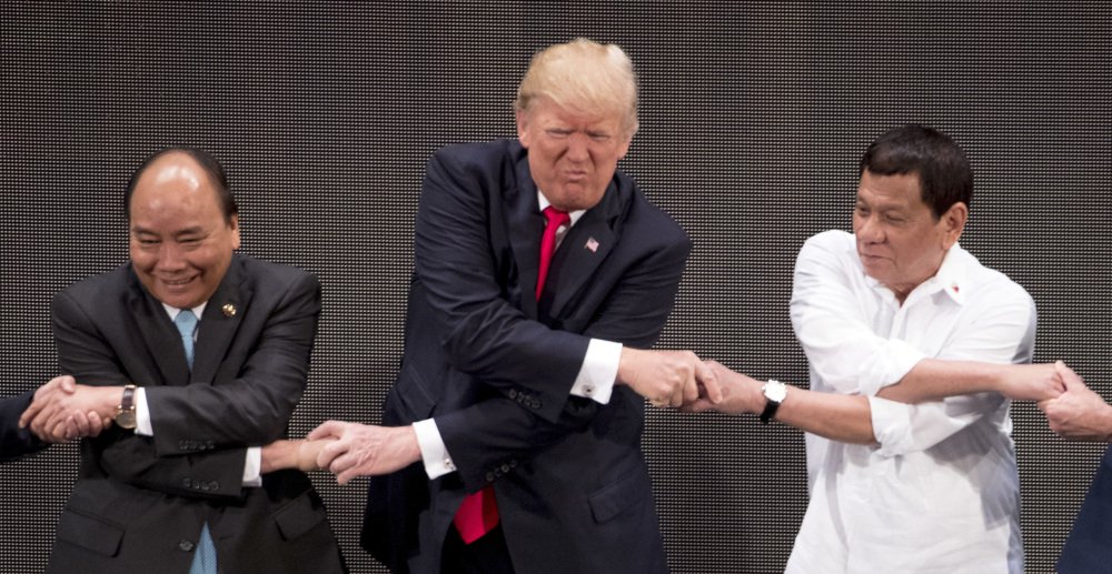 President Trump reacts during the "traditional" ASEAN handshake with Vietnamese President Tran Dai Quang, left, and Philippines President Rodrigo Duterte.