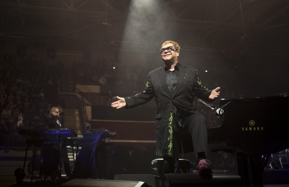 Elton John hops off the piano and gestures toward the excited crowd during his first song at the Cross Insurance Arena on Friday night.