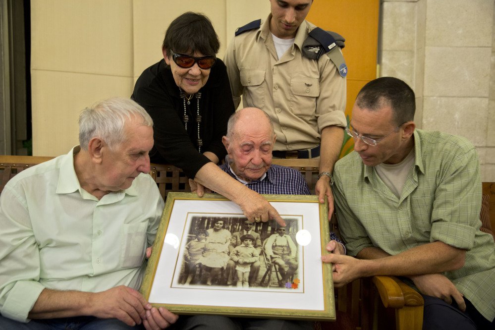 Israeli Holocaust survivor Eliahu Pietruszka, center, looks at a picture with Alexandre Pietruszka and family in the central Israeli city of Kfar Saba. Pietruszka who fled Poland at the beginning of World War II and thought his entire family had perished learned that a younger brother had also survived, and his son, 66-year-old Alexandre, flew from Russia to see him.