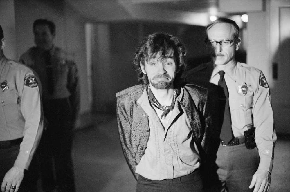 Charles Manson reacts to photographers as he goes to lunch after an outbreak in court that resulted in his ejection in 1970, along with three female co-defendants, during the Sharon Tate murder trial. Authorities say Manson, cult leader and mastermind behind 1969 deaths of Tate and several others, died on Sunday. He was 83.