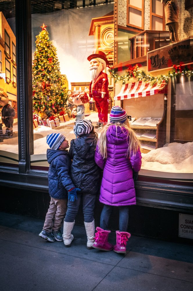 Children look in Macy's storefront window in New York City on a chilly evening. Inside, they can make a reservation to visit Santa.