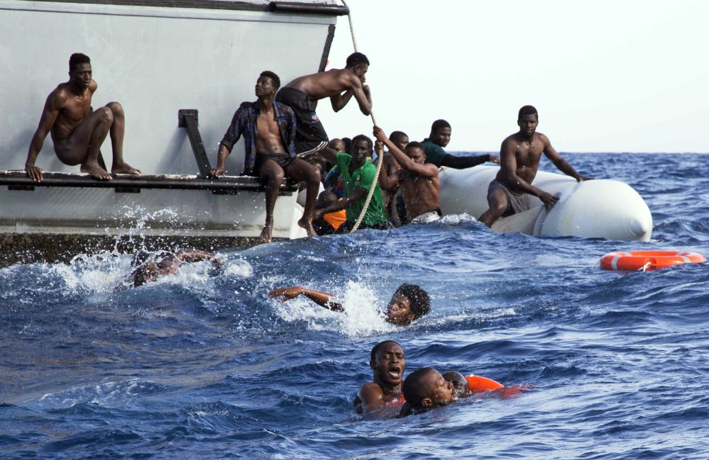 Migrants from a dinghy try to board a Libyan coast guard ship during a rescue operation off the coast of Libya Nov. 6. Researchers have linked some migration to climate change.
