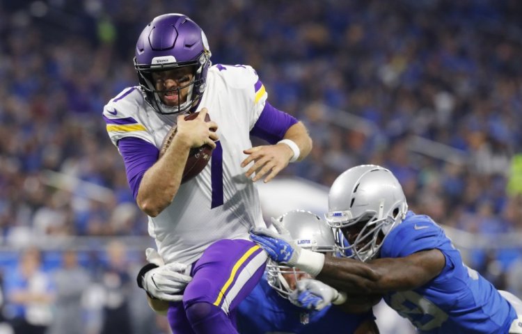 Minnesota quarterback Case Keenum, left, pulls away from the Detroit defense to score on a 9-yard rush in the first half on Thursday. The Vikings won, 30-23.
