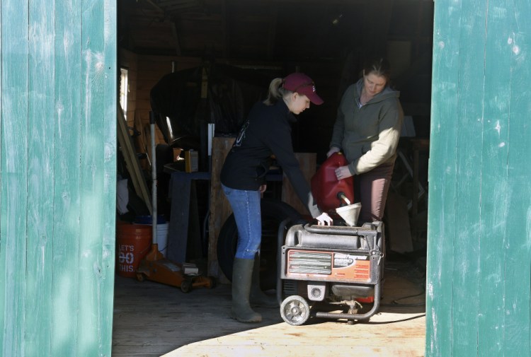 Emma Christman, 17, helps her mother, Jana, fuel a generator Tuesday in the shed at their Litchfield home. Most homes in the town were still without power after Monday's storm.