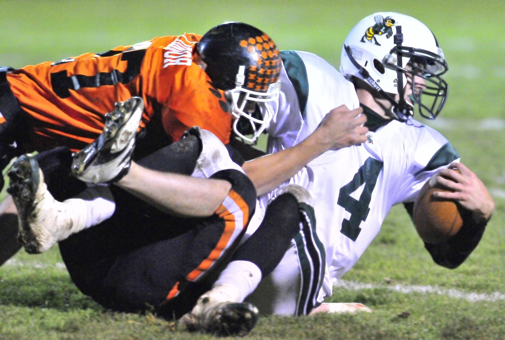 Staff file photo by Joe Phelan 
 Gardiner defensive back Alonzo Connor, left, and Nathan Lapointe, bottom, wrap up Leavitt quarterback Jordan Hersom during a 2010 game at Hoch Field in Gardiner. Hersom is now an assistant coach at Gardiner.