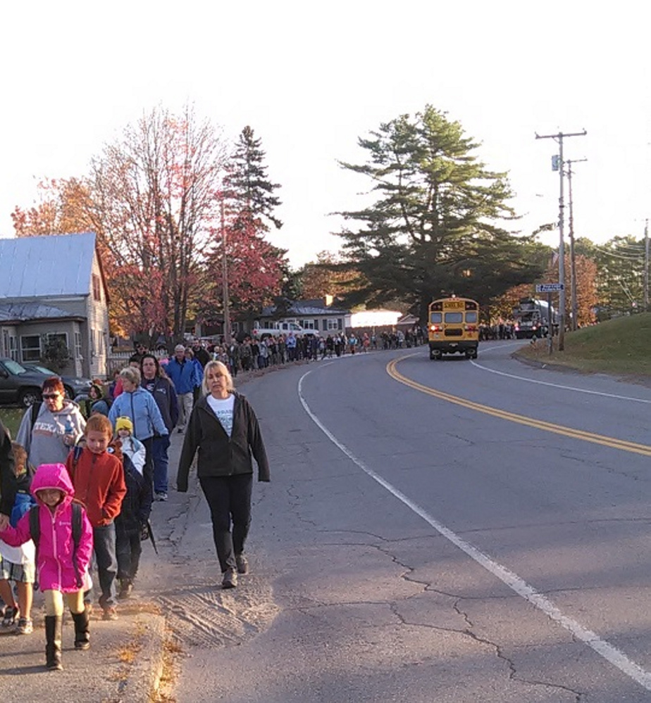 Patti Theberge, a first-grade teacher at Carrabec Community School, takes the lead as a trail of students, which goes back   mile, walk from Carrabec High School to the community school during its October Walking School Bus event.