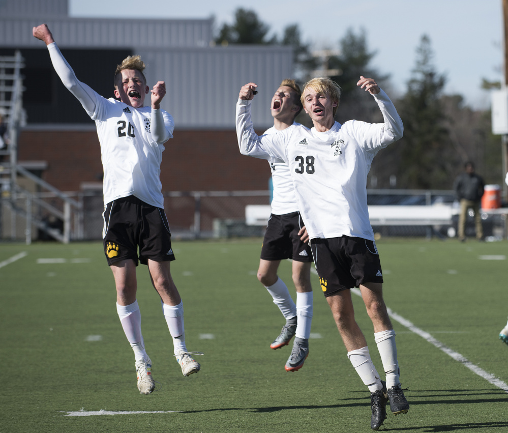 Maranacook players Duncan Rogers, left, Wyatt Lambert, center, and Bryan Riley celebrate Silas Mohlar's goal with 20 seconds left in regulation of the Class C state final against Fort Kent on Saturday morning at Hampden Academy.