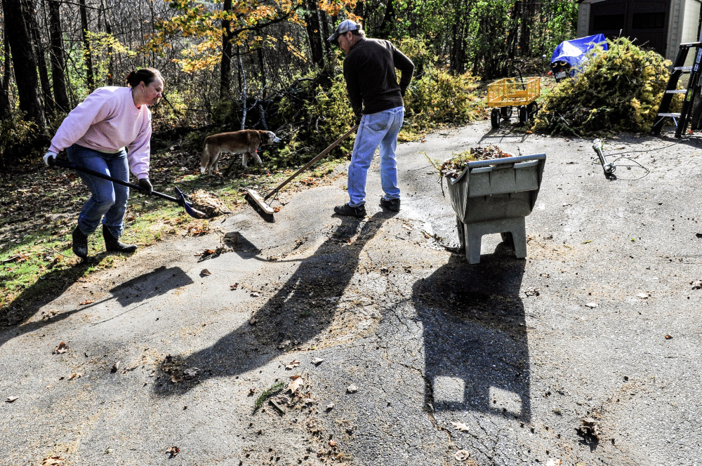 Melinda and Bruce Edwards clean up their property Saturday in Winthrop after having a storm-toppled 76-year-old pine tree that fell in their driveway cut up.