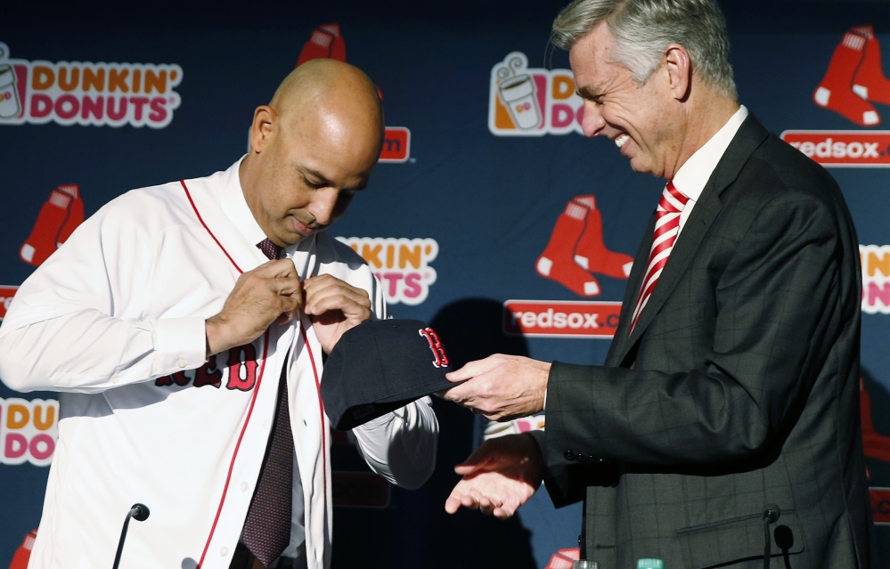 Alex Cora, left, buttons his jersey as he is introduced as new manager of the Boston Red Sox by President of Baseball Operations Dave Dombrowski during a news conference Monday in Boston.