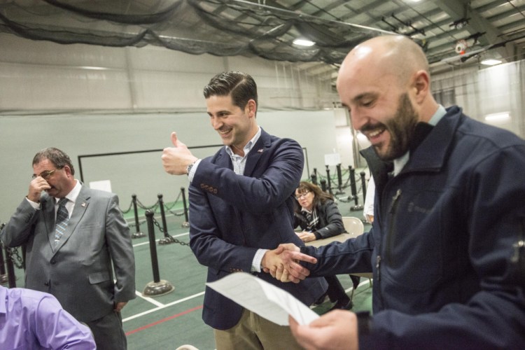Nick Isgro gives a thumbs-up after hearing the results of the Waterville mayoral race Tuesday at Thomas College in Waterville as he shakes hands with Councilor Nick Champagne. Councilor Sydney Mayhew is to the left.