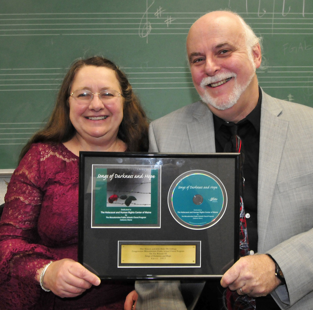 Messalonskee High School Concert Chorus co-directors Pam and Kevin Rhein show copies Thursday of "Songs of Darkness and Hope," performed by Messalonskee students, which is nominated for a Grammy award in the choral category.