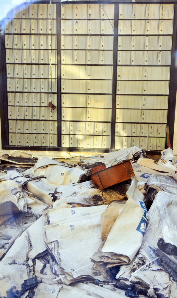 Seen through a window, debris is visible on the lobby floor on Friday inside the burned out U.S. post office in Winthrop.