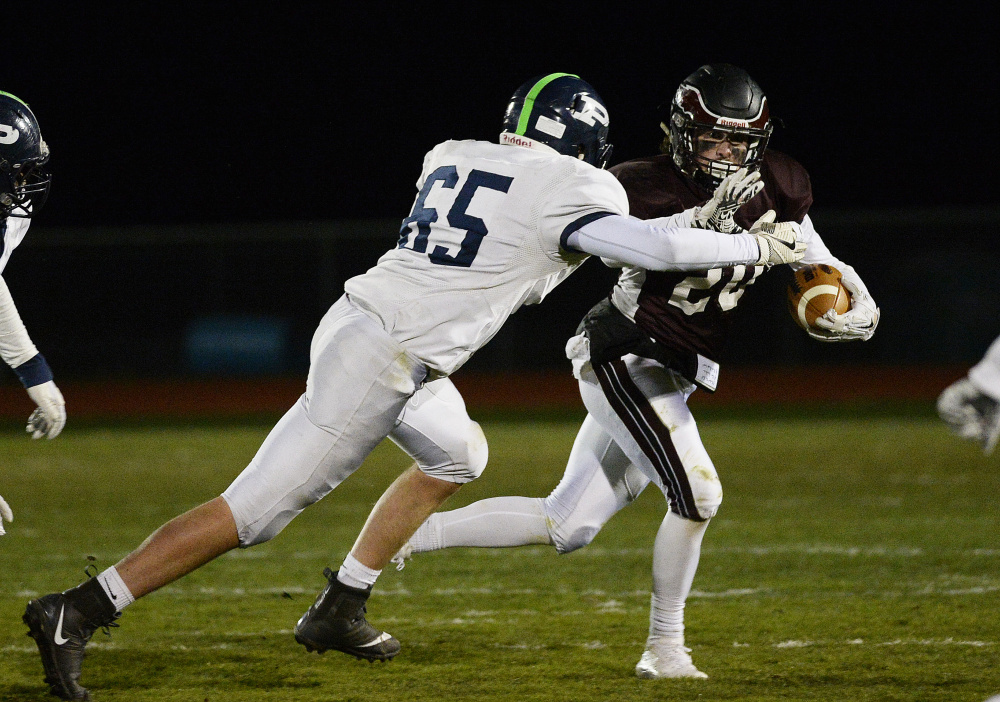 Windham's Tanner Bernier carries the ball as Portland's Jonah Green moves in during the Class A North football championship Friday night at Windham High.