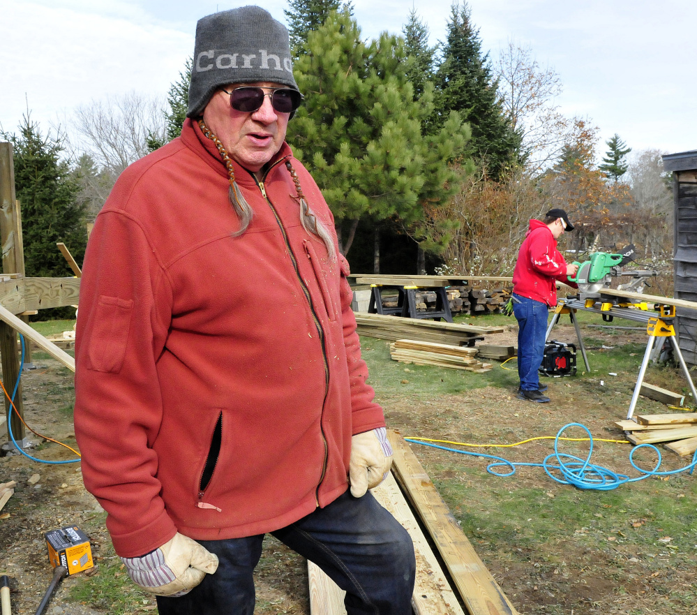 Phil White Hawk talks about the new wheelchair ramp under construction at the Palermo Community Center on Sunday. At right Brian Taylor cuts wood for the project.