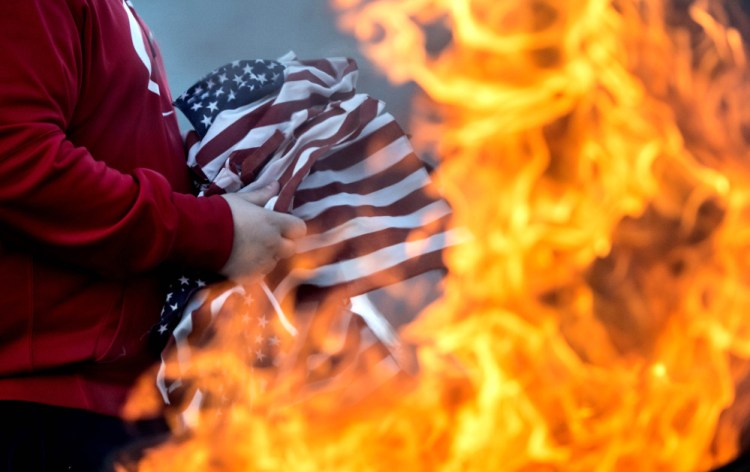 Alex Drayton retires old and tattered American flags during a ceremonial burning at the Peter-Shortier American Legion Post 16 on Saturday.