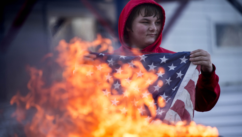 Alex Drayton retires old and tattered American flags during a ceremonial burning at the Peter-Shortier American Legion Post 16 on Saturday.