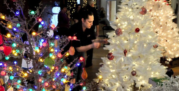 Janice Partridge, of Cappza's Pizza, decorates the company-sponsored tree at right Tuesday, next to another tree for the upcoming Sukeforth Family Festival of Trees at the Hathaway Creative Center in Waterville.