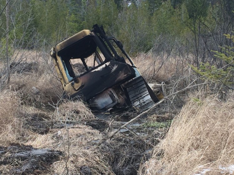 This bulldozer, owned by Cousineau Wood Products of Wilton, was found by hunters Tuesday off Beech Hill Road in Sandy River Plantation, where it had been set on fire.