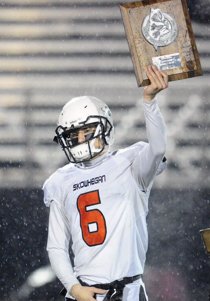 Skowhegan captain Sean Savage holds up the runnerup plaque after the Class B state game Saturday night in Portland.