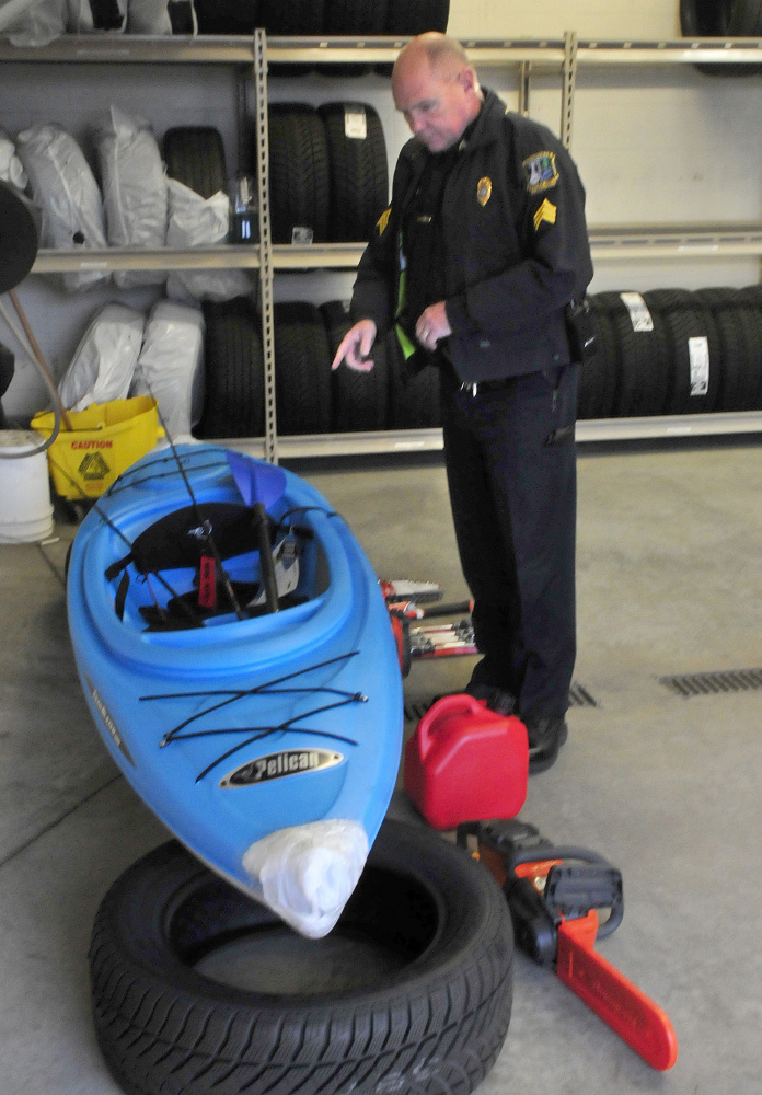 Waterville police Sgt. Alden Weigelt looks over some of the items recovered Wednesday outside the Hathaway Creative Center that had been taken sometime Sunday night from various vendors at the Sukeforth Family Festival of Trees. They include a kayak, tools, fishing equipment and a chain saw. Bobby Campbell, a transient, has been charged with burglary and theft.