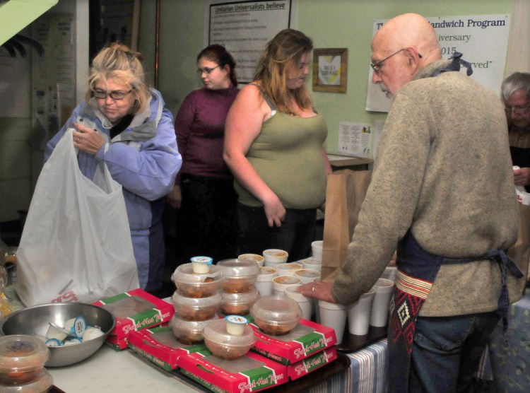 Recipients of the Unitarian Universalist Church Evening Sandwich program select food from volunteer Bruce O'Donnell at the church in Waterville on Tuesday. From left are Evonne Barter, Brittany Beech and Kathy Quimby.