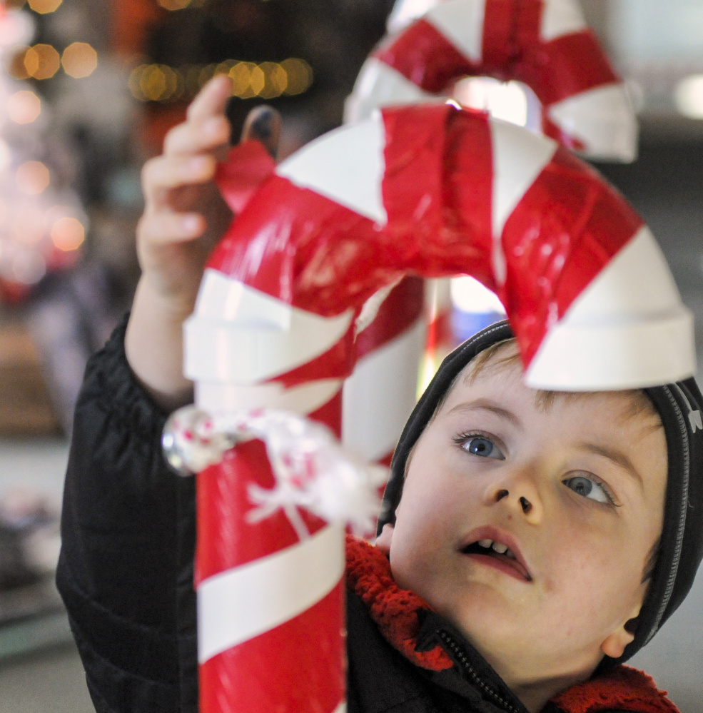 Nicky Mitchell, 4, of Gardiner, drops a ticket into a PVC pipe candy cane to vote for one of his favorite trees Friday at the River of Trees event in downtown Augusta.