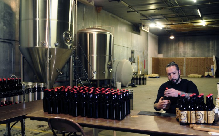 Owner David Boucher puts labels bottles at Lost Orchard Brewing Company on March 4, 2016 in South Gardiner. The facility has since closed and the former church in Gardiner that was to be used as a tasting room is up for auction.