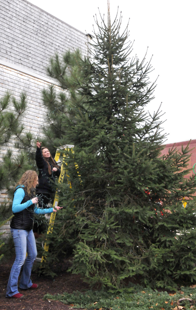Main Street Skowhegan board member Darcy Spooner, left, and volunteer Mary Haley remove old Christmas lights from trees in the park in downtown Skowhegan before stringing new lights Wednesday for the upcoming 25th annual Holiday Stroll.