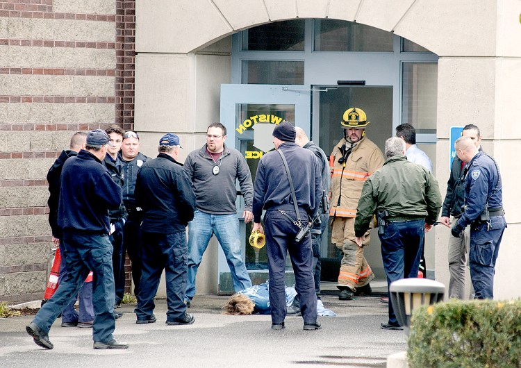 A woman lies on the ground as rescue personnel gather outside the Lewiston Police Department after she was removed from the department lobby, where she threatened to set herself afire. 
