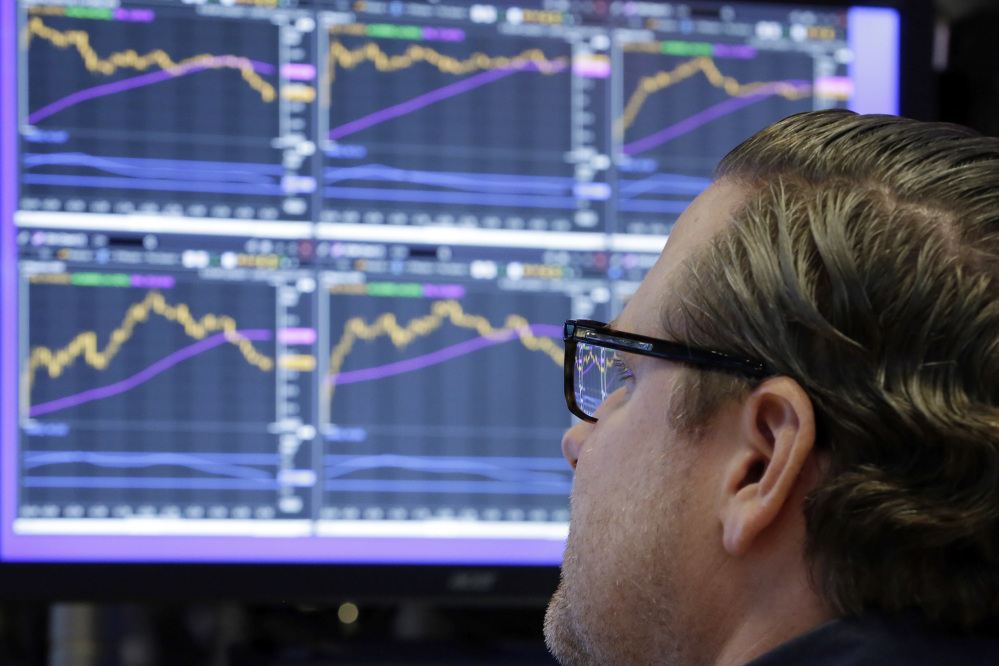 Specialist Gregg Maloney works Monday at his post on the floor of the New York Stock Exchange. The exchange was nearly evenly split between stocks that rose and fell.