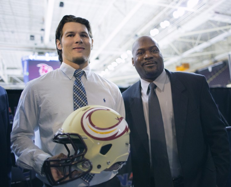 Jonathan Bane, quarterback of the Maine Mammoths, a new National Arena League football team based in Portland, displays the team's helmet design with head coach James Fuller after a news conference Tuesday at Cross Insurance Arena. (Photo by Derek Davis/Staff photographer)