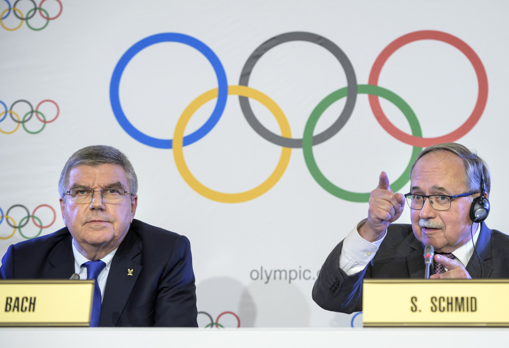 International Olympic Committee President Thomas Bach from Germany, left, and Samuel Schmid, president of the IOC Inquiry Commission and former president of Switzerland, right, comment during a news conference in Lausanne, Switzerland, on Tuesday.  Russian athletes will be allowed to compete at the upcoming Pyeongchang Olympics as neutrals despite orchestrated doping at the 2014 Sochi Games, the International Olympic Committee said.