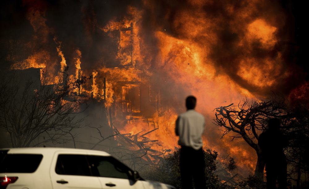 Associated Press/Noah Berger
A man watches flames consume a home as a wildfire rages in Ventura, Calif., on Tuesday. Ferocious winds in Southern California have whipped up explosive wildfires, burning a psychiatric hospital and scores of other structures.