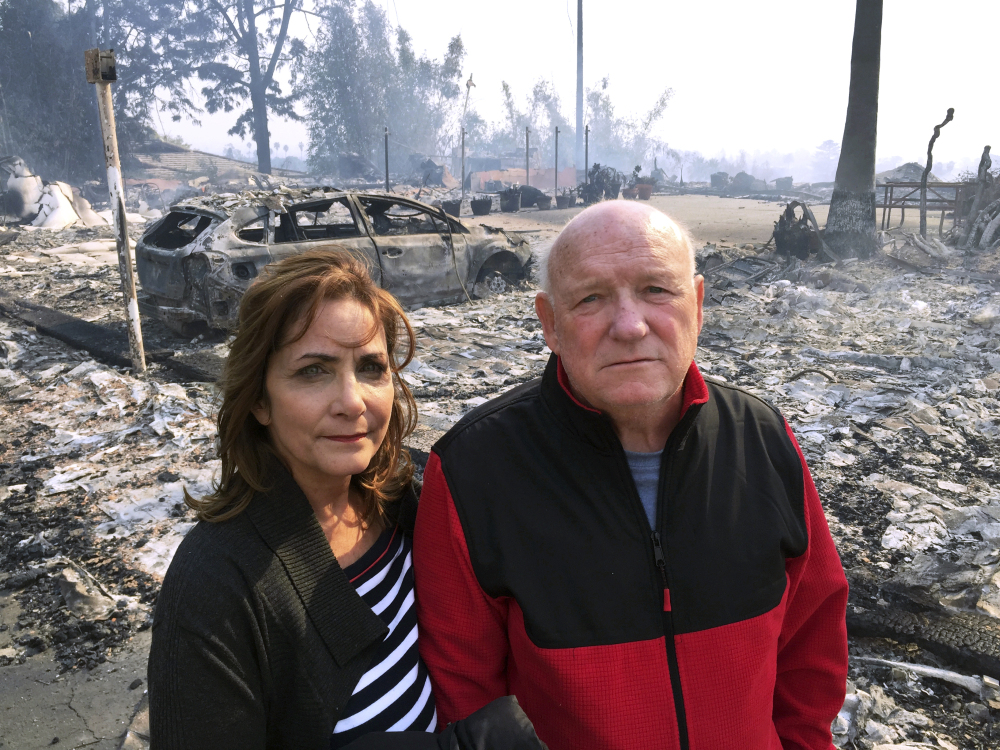 Linda and John Keasler pose for a photo Tuesday in front of the ruins of their home at the Hawaiian Village Apartments, which was destroyed by fire. "It is sad," said John Keasler, 65." We loved this place. We lost everything."
