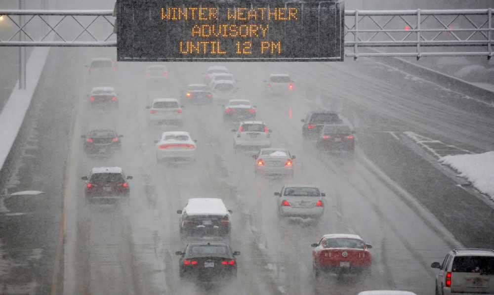 A heavy morning snow falls in Jackson, Miss., Friday, as an electronic sign posts a winter weather advisory on Interstate 55.