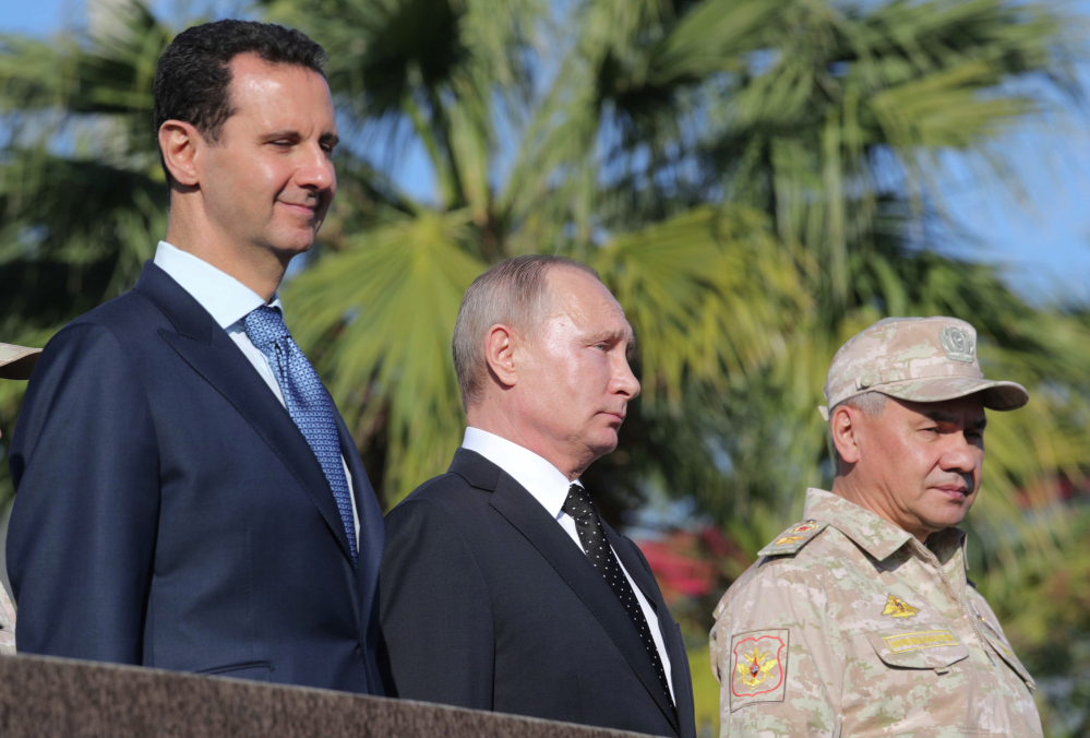 From left, Syrian President Bashar Assad, Russian President Vladimir Putin and Russian Defence Minister Sergei Shoigu watch troops march at Syria's Hemeimeem air base Monday.