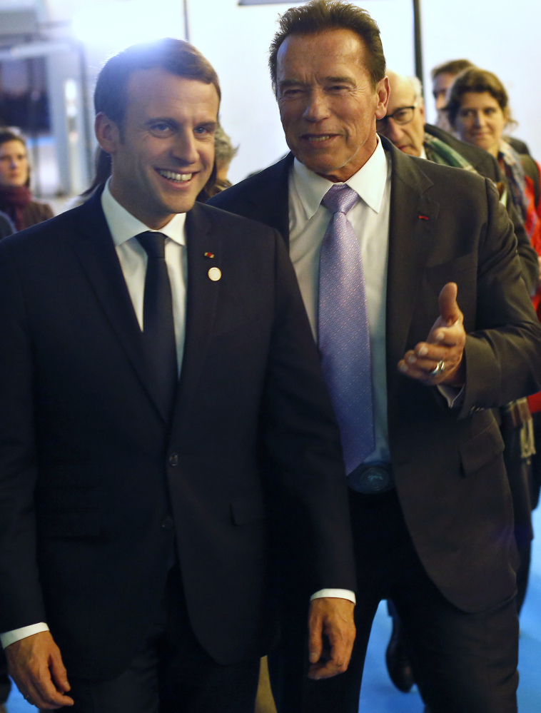 France's President Emmanuel Macron, left, and Arnold Schwarzenegger leave the One Planet Summit near Paris, Tuesday. American leaders there said the world will go greener with or without President Trump.accord.