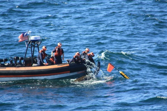 A crew deployed from the Coast Guard Cutter Campbell untangles a 6-foot-long leatherback turtle from fishing line 15 miles off Cape Elizabeth in September 2015. After cutting the line, the crew watched as the turtle swam away to the open sea. Regulators are considering whether to classify the turtles as an endangered species.